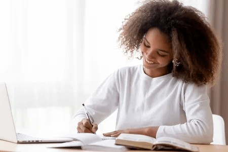 123628443-adolescente-afro-américaine-souriante-préparant-les-devoirs-de-l-école-utilisant-un-ordinateur-porta